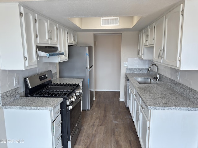 378 Hourglass Dr, El Paso, TX 79915 - kitchen with stainless steel range with gas cooktop, under cabinet range hood, white cabinets, dark wood finished floors, and tasteful backsplash