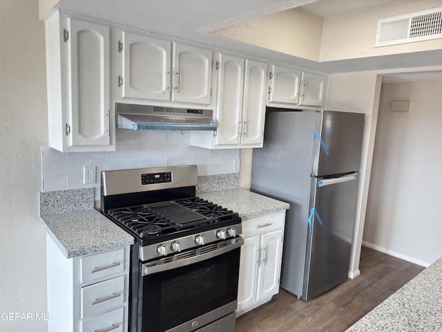378 Hourglass Dr, El Paso, TX 79915 - kitchen with appliances with stainless steel finishes, under cabinet range hood, dark wood-style flooring, white cabinets, and tasteful backsplash