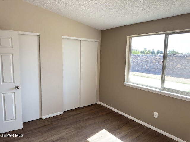 378 Hourglass Dr, El Paso, TX 79915 - unfurnished bedroom featuring dark wood-style floors, multiple closets, and a textured ceiling