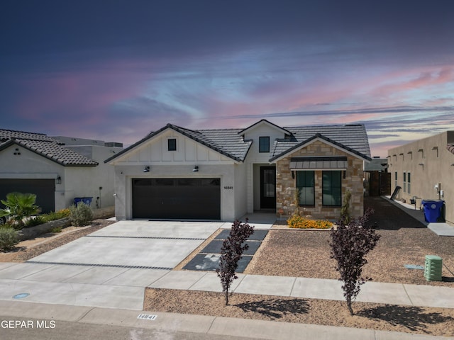 14841 Mike A Mendoza Ave, El Paso, TX 79938 - view of front of property with board and batten siding, an attached garage, concrete driveway, stone siding, and a tile roof