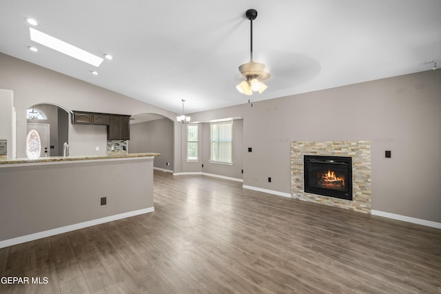 3928 Tierra Roman Dr, El Paso, TX 79938 - unfurnished living room with arched walkways, a fireplace, wood finished floors, a ceiling fan, and lofted ceiling