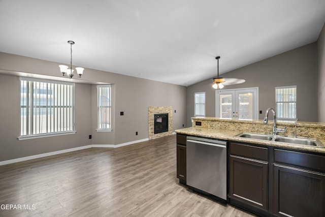 3928 Tierra Roman Dr, El Paso, TX 79938 - kitchen with stainless steel dishwasher, open floor plan, a glass covered fireplace, pendant lighting, and light wood-style flooring