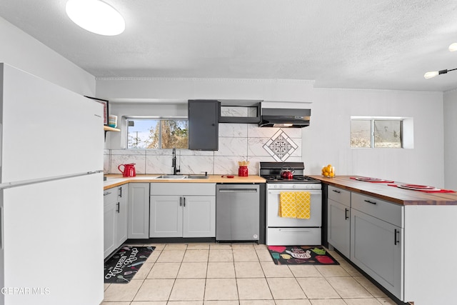 5656 Dailey Ave, El Paso, TX 79905 - kitchen with white appliances, extractor fan, decorative backsplash, butcher block countertops, and light tile patterned flooring