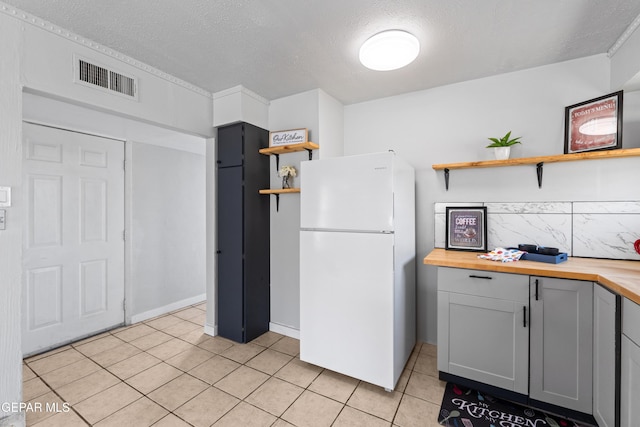 5656 Dailey Ave, El Paso, TX 79905 - kitchen featuring freestanding refrigerator, open shelves, butcher block counters, light tile patterned flooring, and a textured ceiling