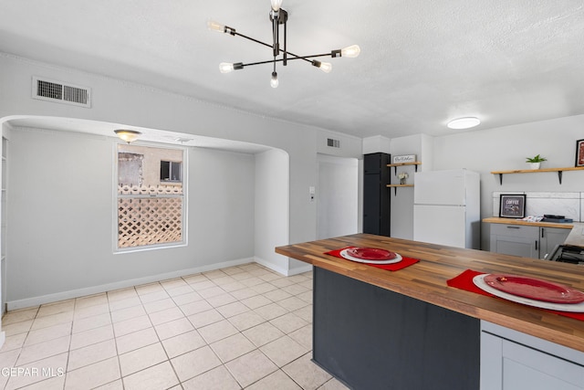 5656 Dailey Ave, El Paso, TX 79905 - kitchen featuring wood counters, freestanding refrigerator, open shelves, a chandelier, and a textured ceiling