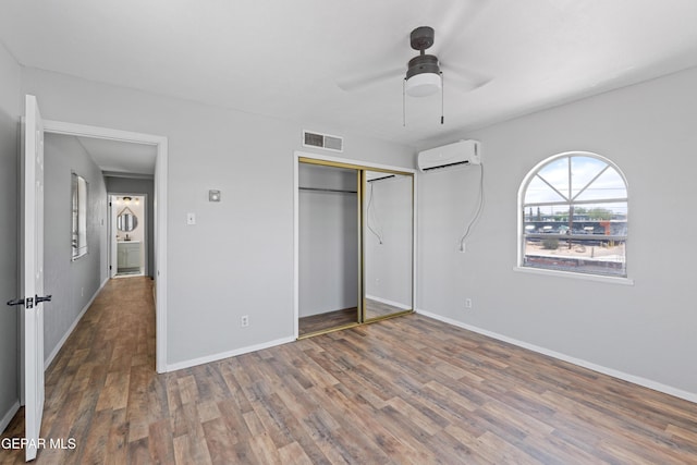 5656 Dailey Ave, El Paso, TX 79905 - unfurnished bedroom featuring a wall mounted AC, wood finished floors, a closet, and a ceiling fan