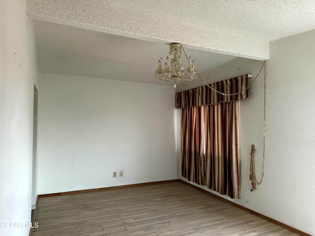 9212 Atun Way, El Paso, TX 79907 - empty room with a chandelier, wood finished floors, and a textured ceiling