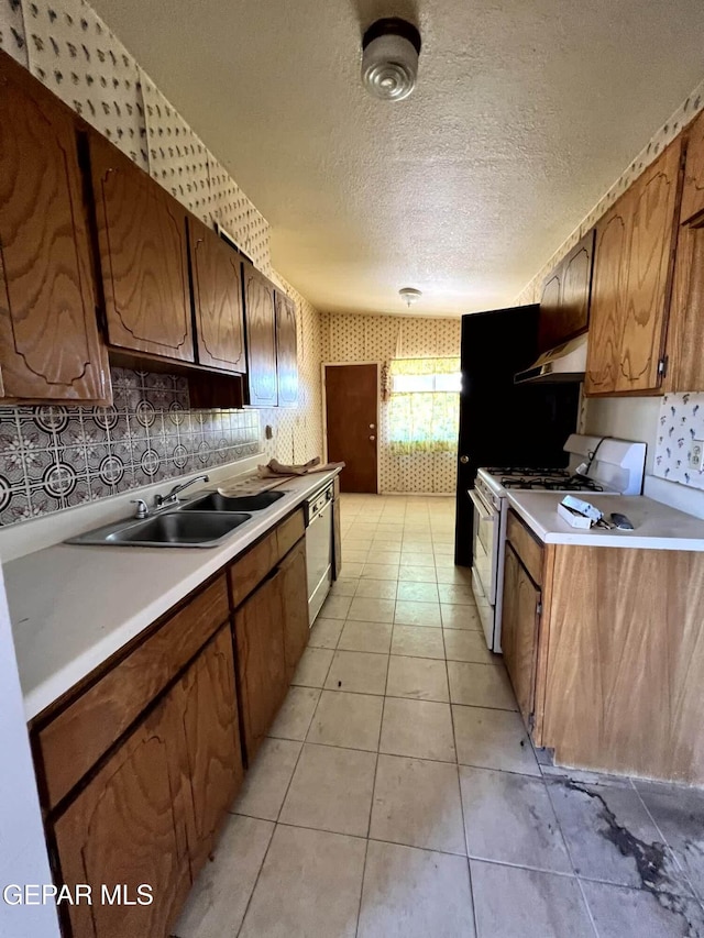 9212 Atun Way, El Paso, TX 79907 - kitchen with white gas range oven, under cabinet range hood, dishwasher, light countertops, and wallpapered walls