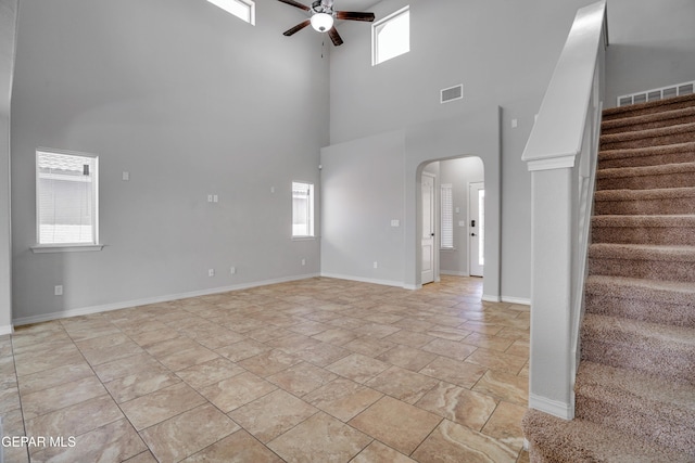 7548 Wolf Creek Dr, El Paso, TX 79911 - unfurnished living room featuring a high ceiling, ceiling fan, arched walkways, stairway, and light stone finish floors