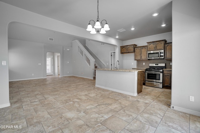 7548 Wolf Creek Dr, El Paso, TX 79911 - kitchen with stainless steel appliances, arched walkways, tasteful backsplash, decorative light fixtures, and a chandelier