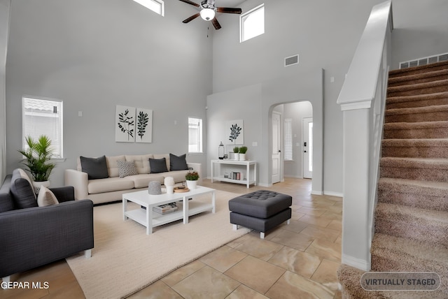 7548 Wolf Creek Dr, El Paso, TX 79911 - living area featuring ceiling fan, a towering ceiling, arched walkways, stairs, and stone tile flooring