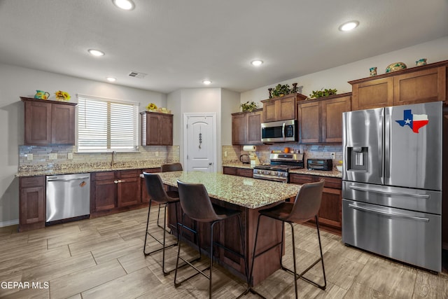 10625 Hidden Links Pl, El Paso, TX 79924 - kitchen with stainless steel appliances, tasteful backsplash, a breakfast bar, light stone counters, and recessed lighting