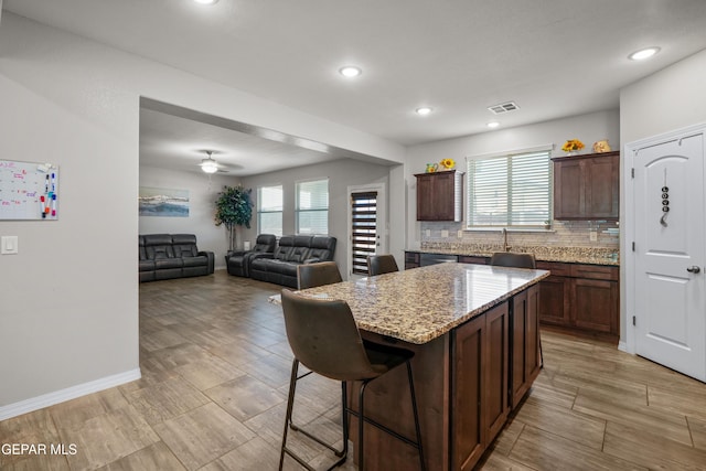 10625 Hidden Links Pl, El Paso, TX 79924 - kitchen featuring a kitchen island, decorative backsplash, a breakfast bar area, recessed lighting, and light stone counters