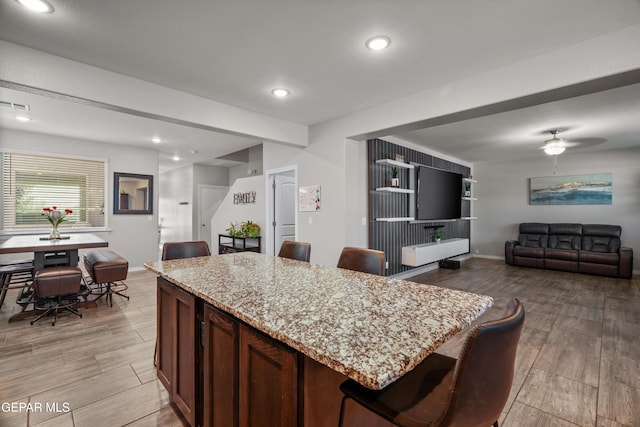 10625 Hidden Links Pl, El Paso, TX 79924 - kitchen featuring light stone countertops, light wood-style floors, open floor plan, a kitchen island, and a breakfast bar