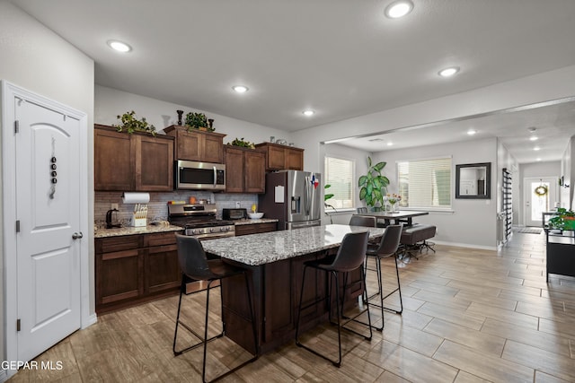 10625 Hidden Links Pl, El Paso, TX 79924 - kitchen featuring stainless steel appliances, a kitchen breakfast bar, a center island, backsplash, and wood tiled floors