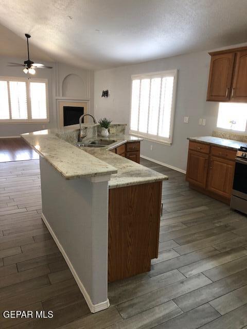 6392 Franklin Gate Dr, El Paso, TX 79912 - kitchen featuring white gas stove, dark wood-style flooring, ceiling fan, and a fireplace