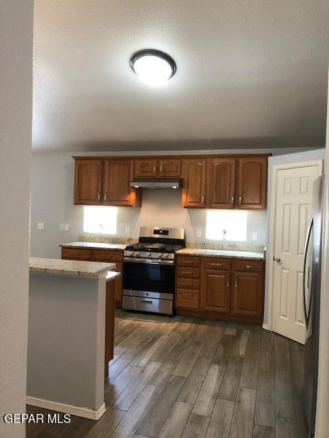6392 Franklin Gate Dr, El Paso, TX 79912 - kitchen with appliances with stainless steel finishes, dark wood-style floors, under cabinet range hood, and brown cabinets