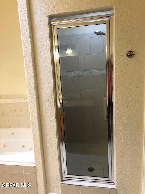 6392 Franklin Gate Dr, El Paso, TX 79912 - full bathroom featuring a shower stall, a tub with jets, and a textured wall