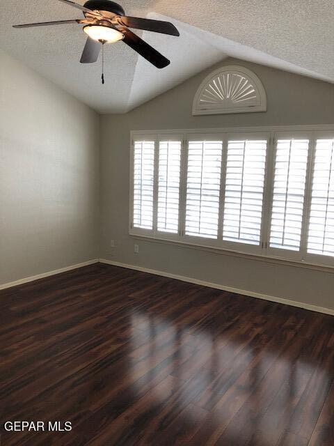 6392 Franklin Gate Dr, El Paso, TX 79912 - unfurnished room featuring vaulted ceiling, a ceiling fan, a textured ceiling, and dark wood finished floors