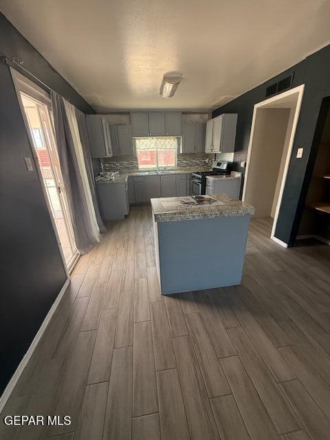 8141 Callison Rd, El Paso, TX 79907 - kitchen featuring gas stove, gray cabinetry, wood finished floors, and tasteful backsplash