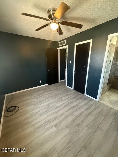 8141 Callison Rd, El Paso, TX 79907 - unfurnished bedroom featuring a textured ceiling, light wood-style flooring, a ceiling fan, and ensuite bathroom