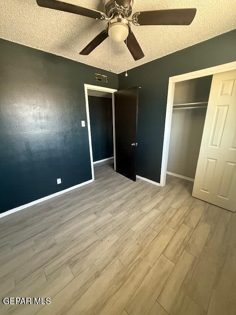 8141 Callison Rd, El Paso, TX 79907 - unfurnished bedroom featuring light wood-style floors, a textured ceiling, a closet, and a ceiling fan
