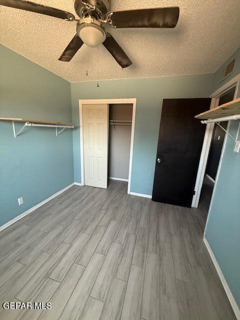 8141 Callison Rd, El Paso, TX 79907 - unfurnished bedroom featuring wood finished floors, a textured ceiling, and a ceiling fan