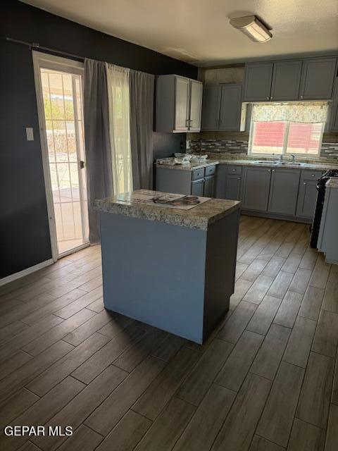 8141 Callison Rd, El Paso, TX 79907 - kitchen with wood finished floors, a center island, tasteful backsplash, and gray cabinets