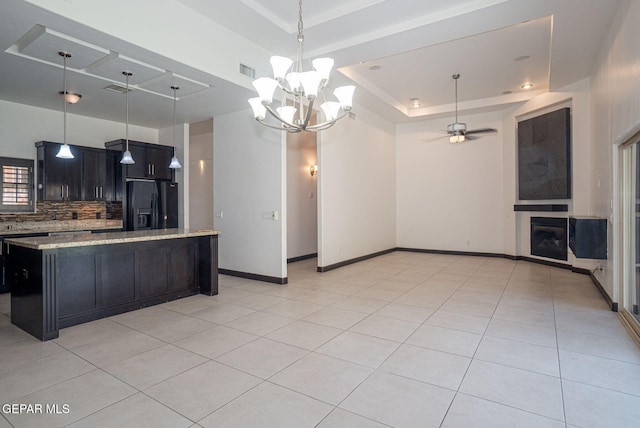 6585 Hermoso Del Sol Dr, El Paso, TX 79911 - kitchen with black fridge, a raised ceiling, tasteful backsplash, a center island, and light stone countertops