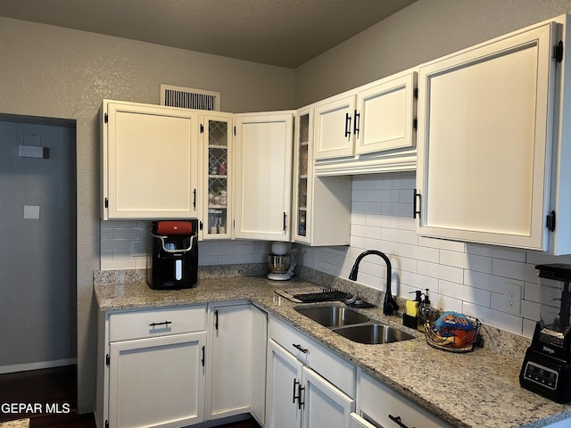 1012 Maple St, El Paso, TX 79903 - kitchen featuring backsplash, white cabinetry, glass insert cabinets, and light stone countertops