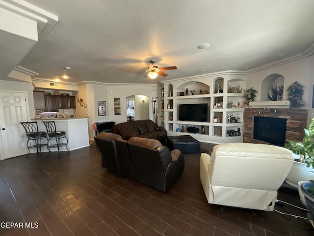 12000 Stansbury Dr, El Paso, TX 79928 - living area featuring ceiling fan, arched walkways, a fireplace, crown molding, and dark wood-style flooring