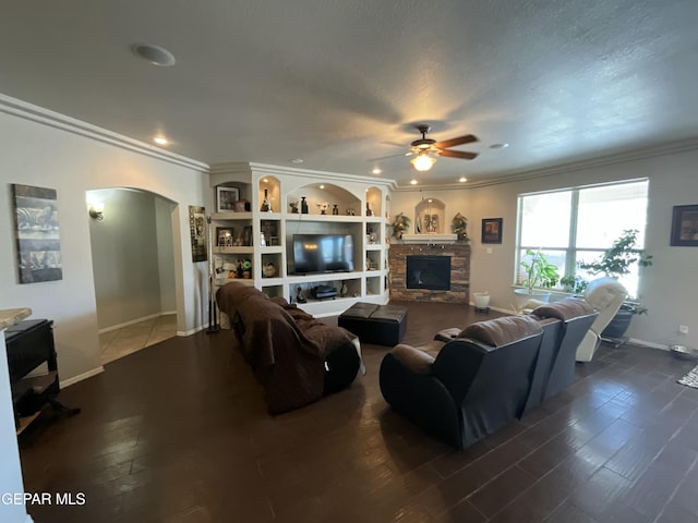 12000 Stansbury Dr, El Paso, TX 79928 - living room with arched walkways, ceiling fan, ornamental molding, dark wood-type flooring, and a stone fireplace