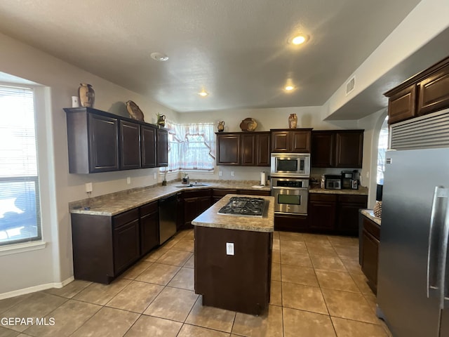 12000 Stansbury Dr, El Paso, TX 79928 - kitchen featuring appliances with stainless steel finishes, dark brown cabinetry, a center island, light tile patterned floors, and recessed lighting