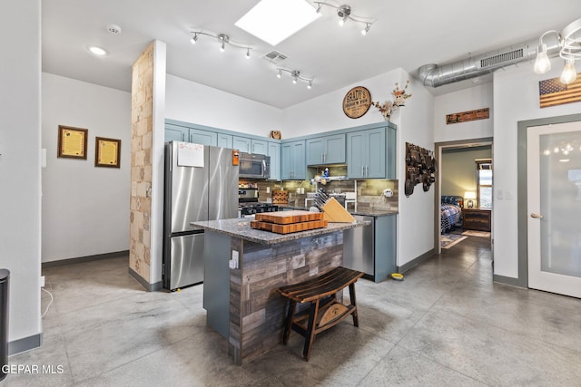 14821 Sunny Land Ave, El Paso, TX 79938 - kitchen with stainless steel appliances, blue cabinetry, finished concrete flooring, dark stone counters, and decorative backsplash