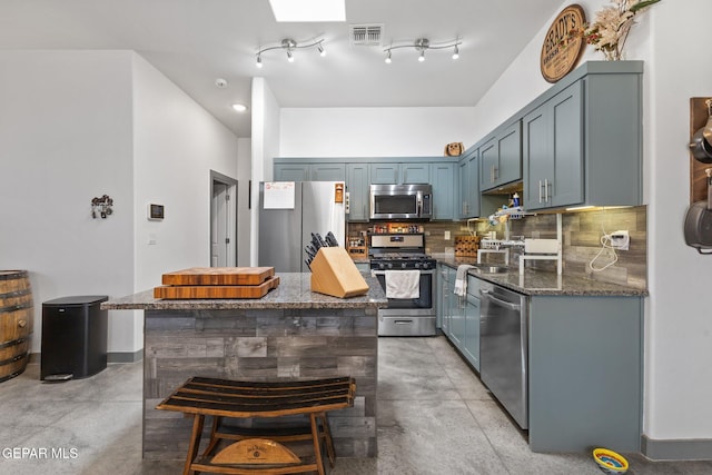 14821 Sunny Land Ave, El Paso, TX 79938 - kitchen with appliances with stainless steel finishes, finished concrete floors, dark stone counters, a center island, and tasteful backsplash
