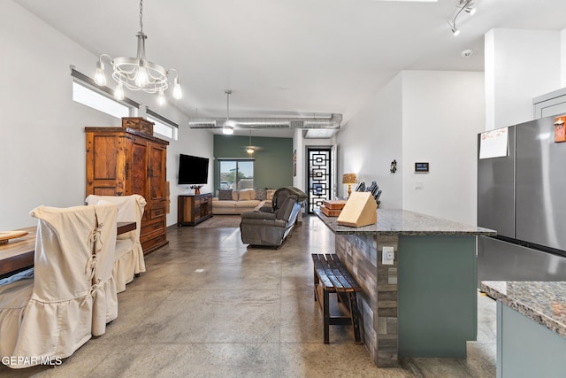 14821 Sunny Land Ave, El Paso, TX 79938 - kitchen featuring freestanding refrigerator, stone counters, a breakfast bar area, a chandelier, and a center island