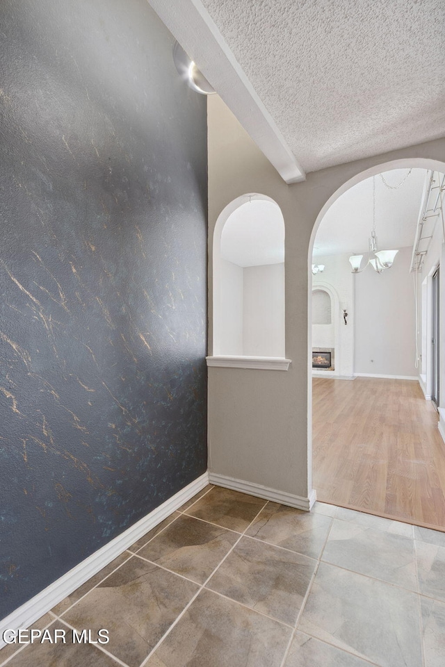 5536 Fernwood Cir, El Paso, TX 79932 - corridor with arched walkways, a chandelier, tile patterned floors, and a textured ceiling