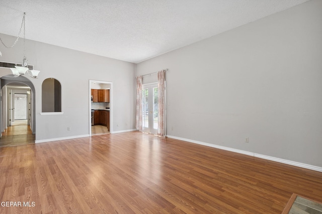 5536 Fernwood Cir, El Paso, TX 79932 - empty room featuring arched walkways, light wood finished floors, a textured ceiling, and a chandelier