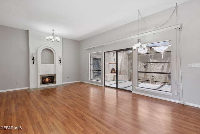 5536 Fernwood Cir, El Paso, TX 79932 - unfurnished living room with a chandelier, healthy amount of natural light, and wood finished floors