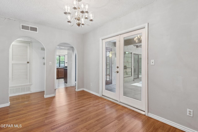 5536 Fernwood Cir, El Paso, TX 79932 - spare room with wood finished floors, arched walkways, a textured ceiling, and a chandelier