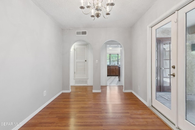 5536 Fernwood Cir, El Paso, TX 79932 - unfurnished dining area with wood finished floors, arched walkways, a textured ceiling, and a chandelier