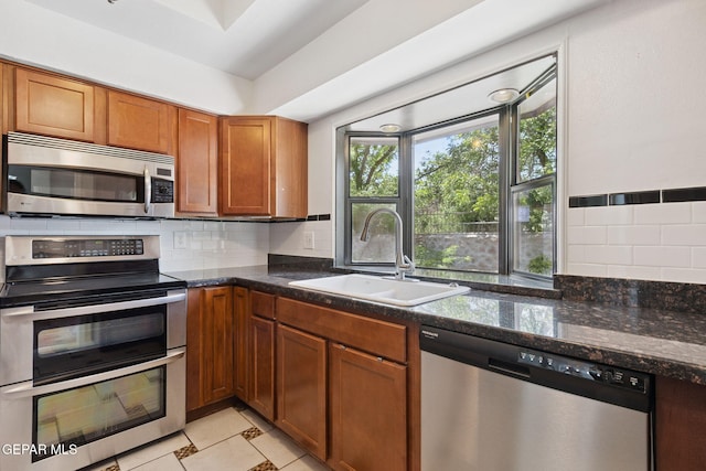 5536 Fernwood Cir, El Paso, TX 79932 - kitchen featuring stainless steel appliances, brown cabinets, decorative backsplash, and dark stone counters