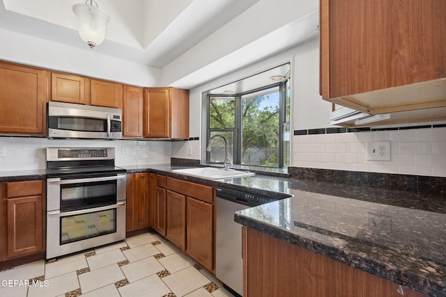 5536 Fernwood Cir, El Paso, TX 79932 - kitchen with appliances with stainless steel finishes, brown cabinets, tasteful backsplash, and dark stone counters
