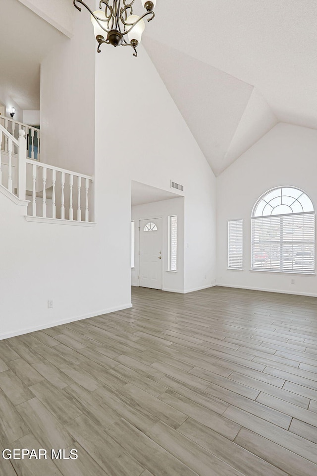 11948 Crown Oaks Ct, El Paso, TX 79936 - unfurnished living room featuring a chandelier, wood finished floors, and high vaulted ceiling