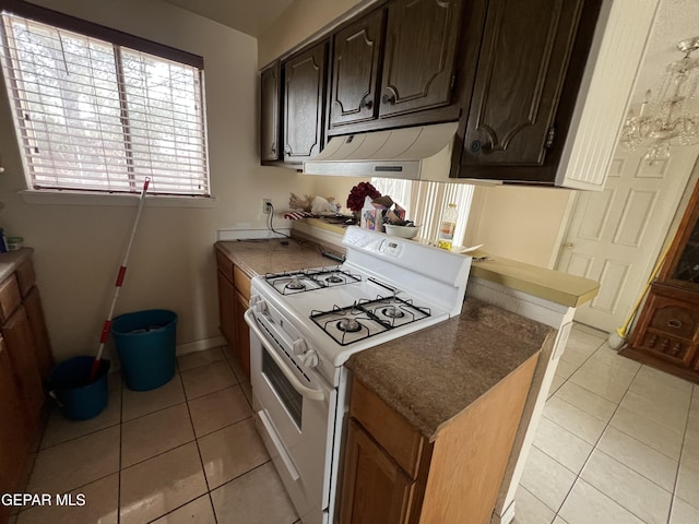 327 Jesuit Dr, El Paso, TX 79907 - kitchen featuring white gas stove, under cabinet range hood, and light tile patterned floors