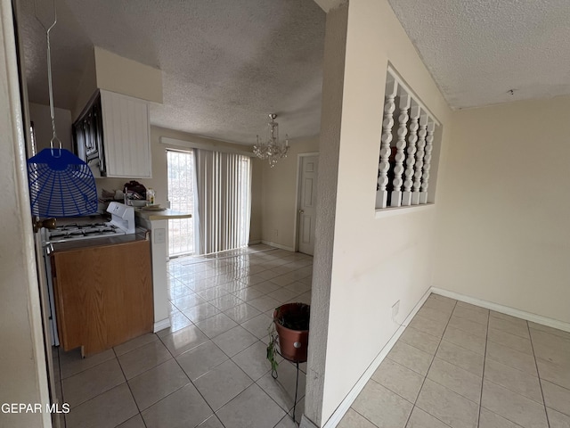 327 Jesuit Dr, El Paso, TX 79907 - kitchen with a textured ceiling, light tile patterned floors, a chandelier, white cabinets, and gas range gas stove