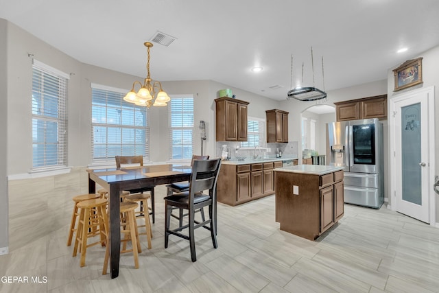 3165 Destiny Point Dr, El Paso, TX 79938 - kitchen featuring stainless steel fridge, a chandelier, a center island, light countertops, and arched walkways