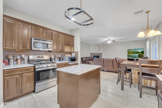 3165 Destiny Point Dr, El Paso, TX 79938 - kitchen with stainless steel appliances, a glass covered fireplace, backsplash, ceiling fan, and open floor plan