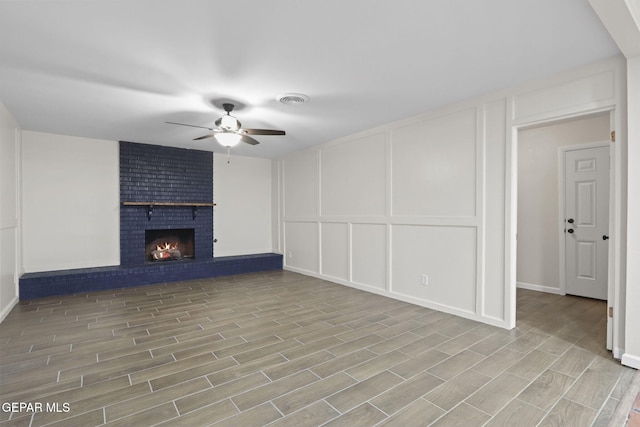 15081 Darrington Rd, Horizon City, TX 79928 - unfurnished living room with a decorative wall, a ceiling fan, wood finished floors, and a fireplace