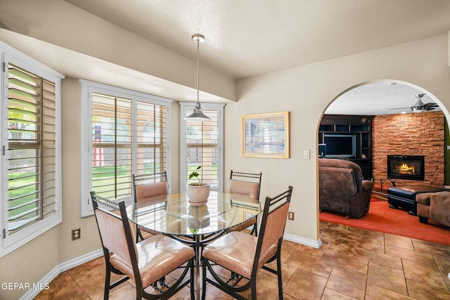 18986 Armington Dr, Horizon City, TX 79928 - dining room with ceiling fan, arched walkways, a textured ceiling, and a fireplace